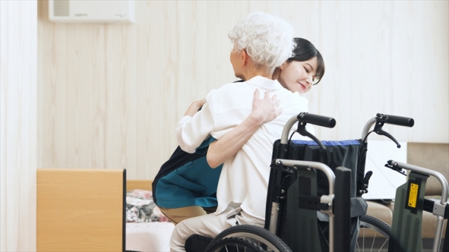 高齢者の移乗介助をする介護士